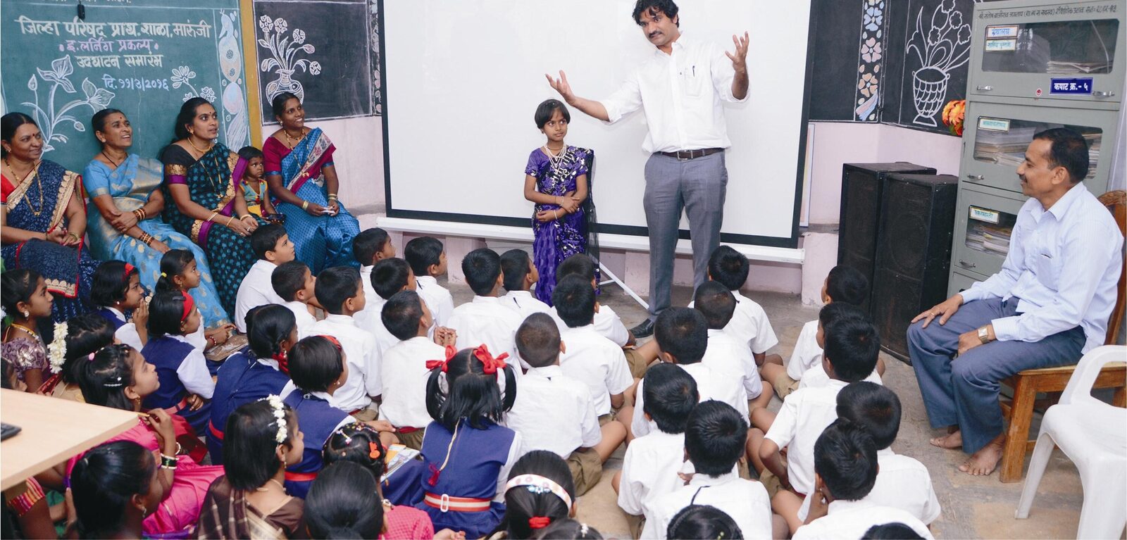 Santosh Talaghatti speaking with a student in front of her class.